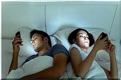 Couples lie in their bed with each their mobile