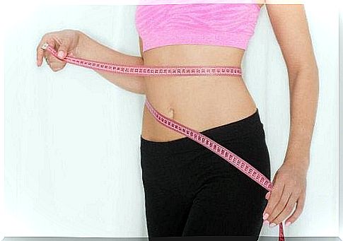 Woman measuring herself around belly with measuring tape