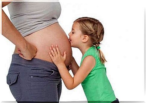 Girl kisses mom's pregnant belly