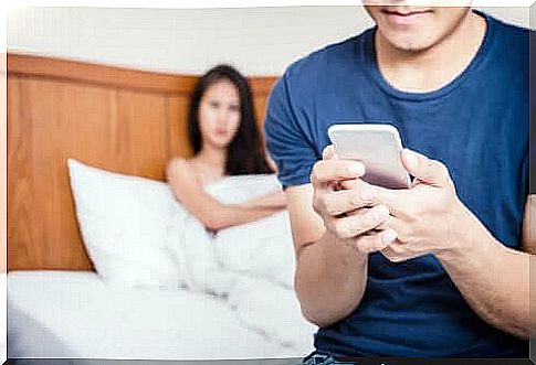 Man in bed with phone in hand and woman in background