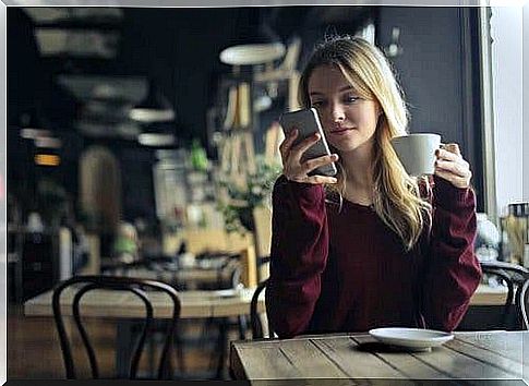 Woman at cafe sitting with her phone